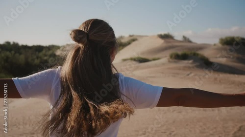 Beautiful young adult blonde woman spinning around in dance and smiling to the morning sun. Hppiness emotion concept photo