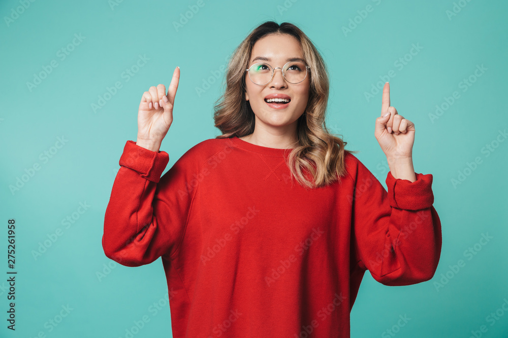 Happy cute young woman posing isolated over white wall background pointing.