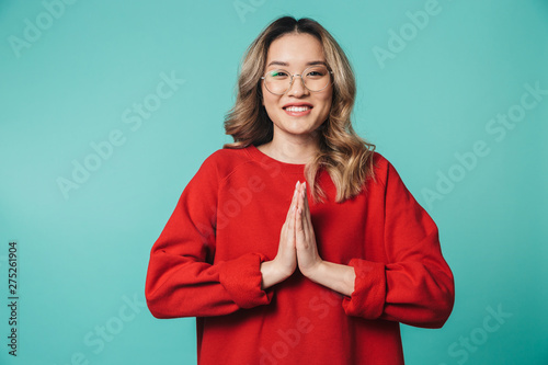 Emotional cute young woman posing isolated over blue wall background make please hopeful gesture.