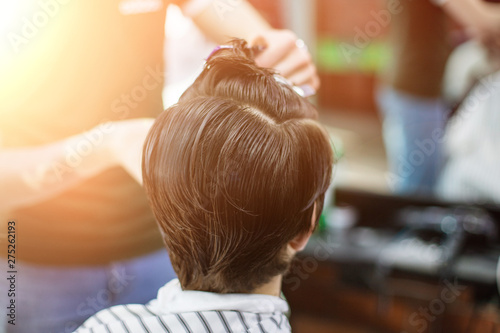 A young successful hairdresser, making an attractive man's haircut in a hairdresser. to cut long hair. man's haircut