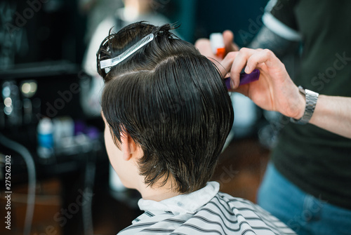 A young successful hairdresser, making an attractive man's haircut in a hairdresser. to cut long hair. man's haircut