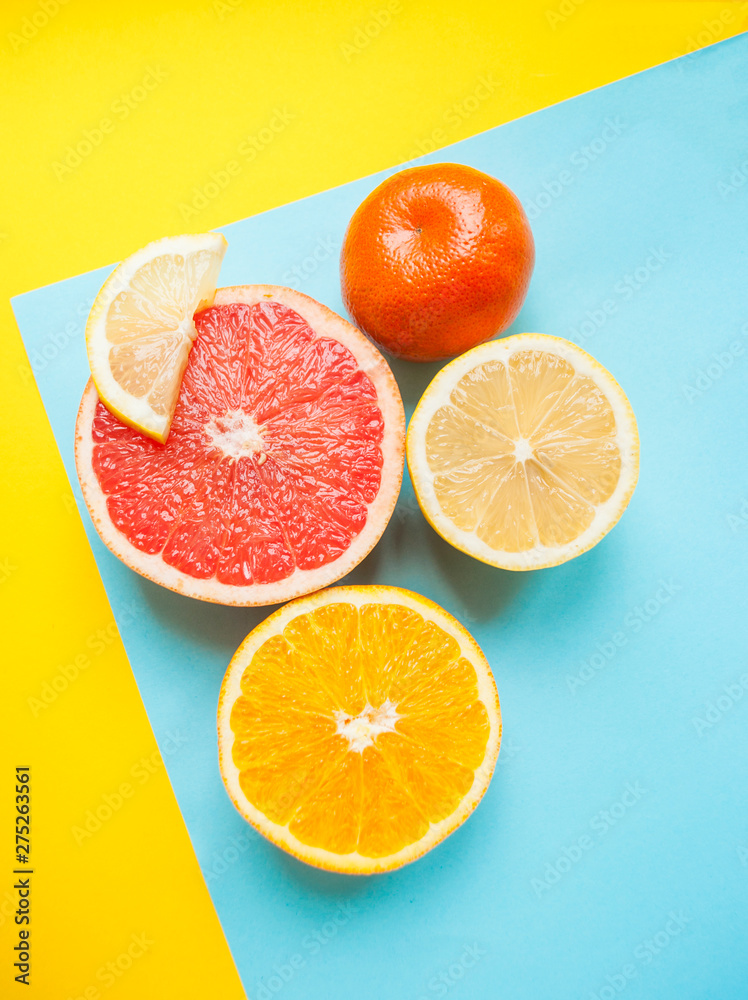 Flat lay of cut ripe juicy grapefruit, lemon and orange on yellow and blue background. Citrus pattern. Flat lay of cut ripe juicy grapefruit, lemon and orange on yellow and blue background. Citrus pattern.