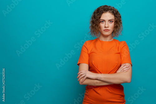 Serious model in orange dress with crossed hands. photo