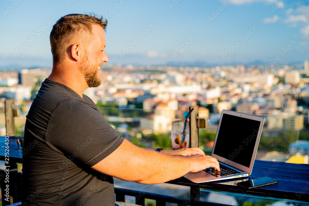 man working on a computer in a cafe with a beautiful view