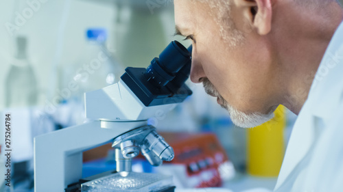 Close-up Portrait Shot of a Male Genetic Research Scientist Working on a Microscope in a Modern High-Tech Laboratory.
