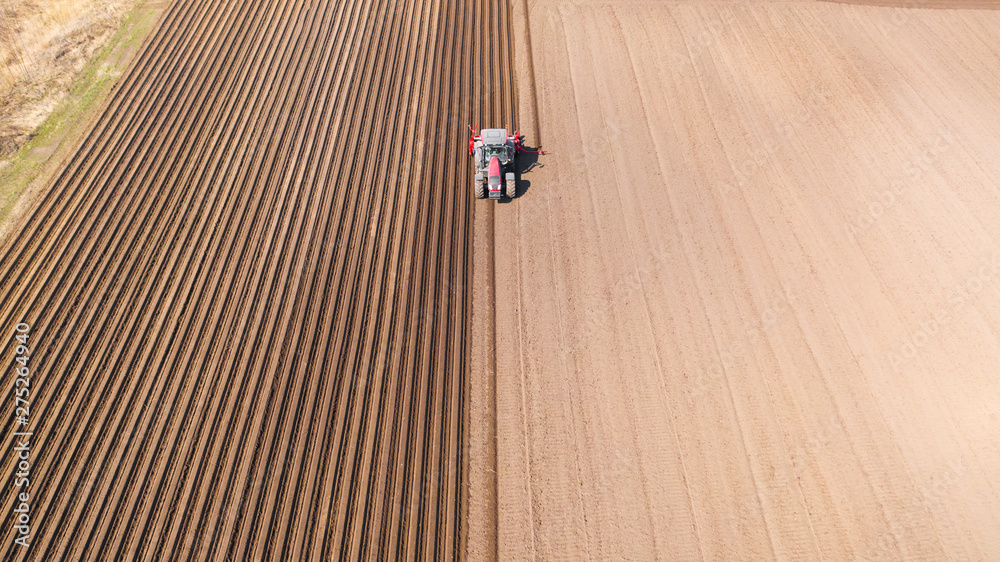 Tractor on a plowed field, top view. Agricultural field for planting vegetables. Tractor makes furrows on the field. Tractor on a plowed field, top view. Agricultural field for planting vegetables. Tractor makes furrows on the field.