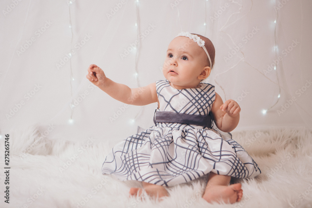 a little girl in a dress sits on the floor on a white background. Child promotes children's clothes a little girl in a dress sits on the floor on a white background. Child promotes children's clothes