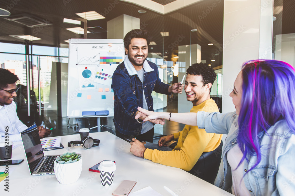 Group of multi ethnic executives discussing during a meeting. Business man and woman sitting around table at office and smiling. A team of young creative designers Group of multi ethnic executives discussing during a meeting. Business man and woman sitting around table at office and smiling. A team of young creative designers