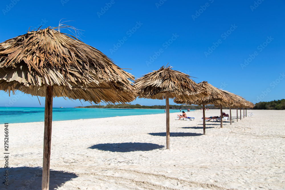 Sun umbrellas on the beach of palm leaves. Horizontally.
