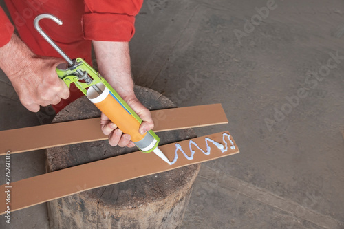 worker applies glue with glue syringe gun