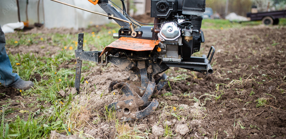 Agricultural machinery: cultivator for tillage in the garden. Preparing the land for planting vegetables with the help of a cultivator. Agricultural machinery: cultivator for tillage in the garden. Preparing the land for planting vegetables with the help of a cultivator.