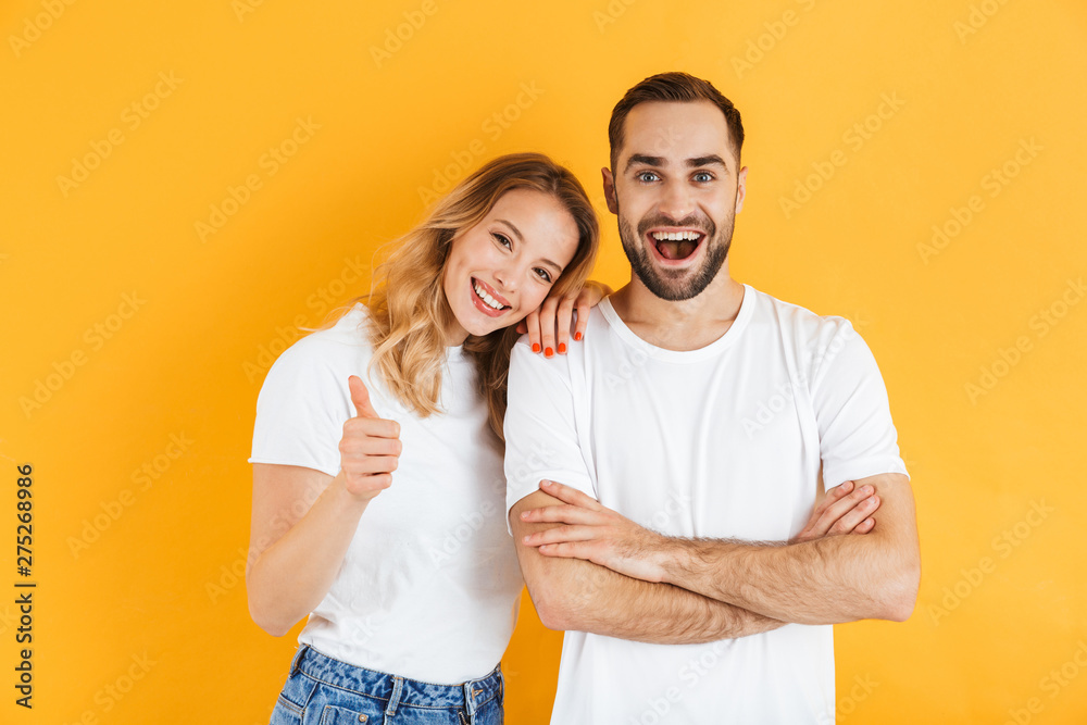 Excited cheerful young couple standing isolated Excited cheerful young couple standing isolated