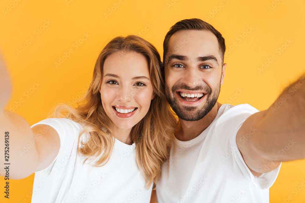Excited cheerful young couple standing isolated Excited cheerful young couple standing isolated
