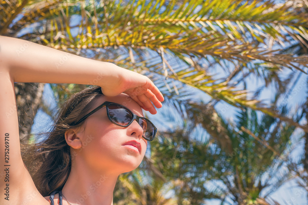 Woman in sunglasses looking on the sky in the palm trees forest. Seychelles islands Woman in sunglasses looking on the sky in the palm trees forest. Seychelles islands