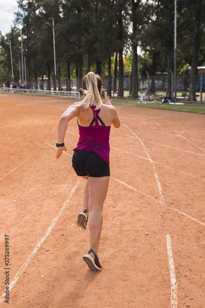 Sporty woman running on stadium track Sporty woman running on stadium track
