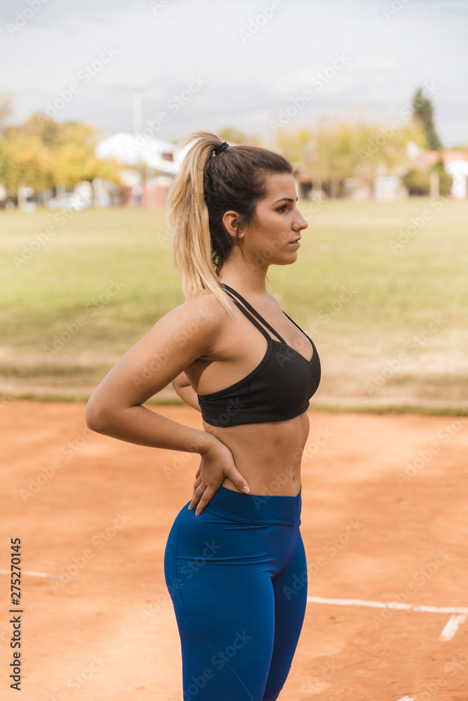 Sporty woman standing on stadium track Sporty woman standing on stadium track