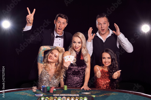 Group of a stylish rich friends are playing poker at casino.