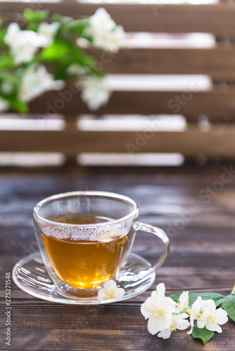 jasmine tea in transparent cup and jasmine flowers on wooden background. Copy space