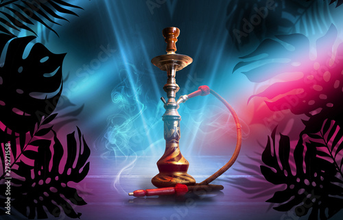 Smoking hookah on a dark abstract background, neon light. Silhouettes of tropical palm leaves in the foreground.