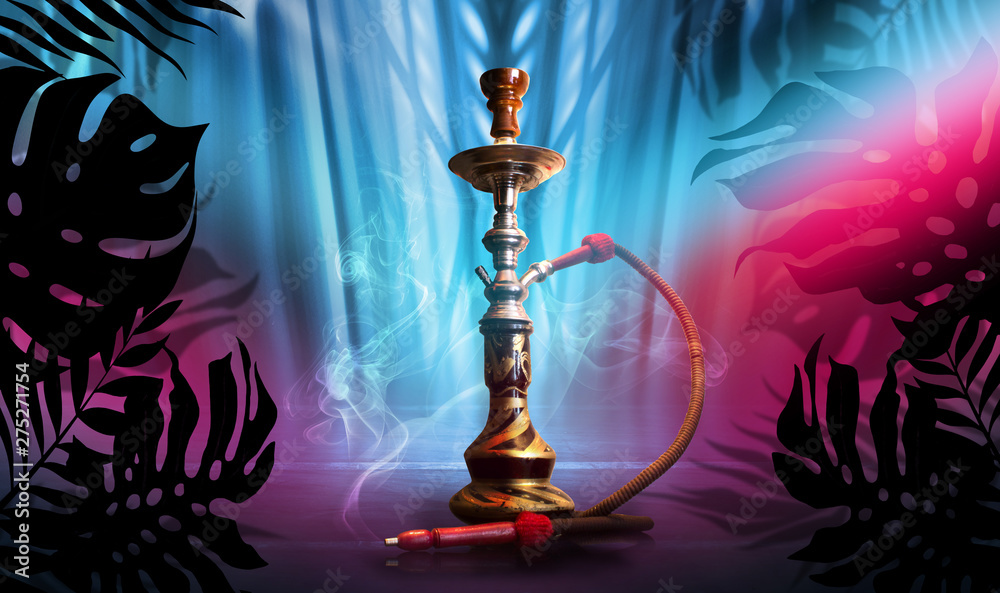 Naklejka premium Smoking hookah on a dark abstract background, neon light. Silhouettes of tropical palm leaves in the foreground.