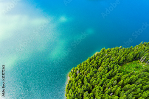Fototapeta Naklejka Na Ścianę i Meble -  Aerial view of a forest lake. Aerial view of blue lake and green forests on a sunny summer day. Drone photography. Forest and lake border, Toned image from above. Coastline view from the drone.