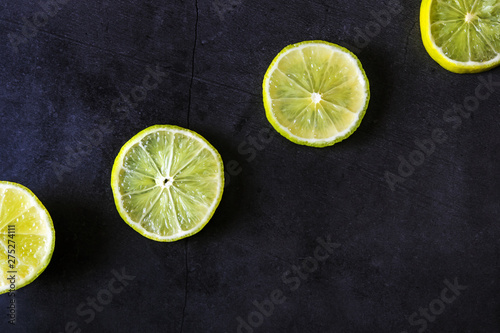 Round lime slices on a black background. Ingredient for smoothies. Background image. Concept of vitamin C, healthy eating, citrus, vegetarianism, organic food. Place for text, minimalism.
