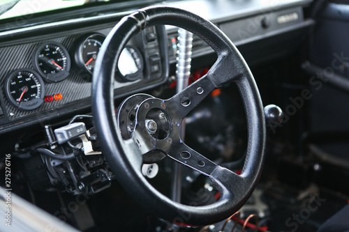 Prepared for racing & reconstructed drift sportcar interior, steering wheel in focus, close up view. Lots of gauges, gear shift knob, glove box blurred in the background. Chrome metal, black plastic.