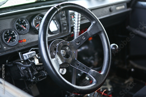 Prepared for racing & reconstructed drift sportcar interior, steering wheel in focus, close up view. Lots of gauges, gear shift knob, glove box blurred in the background. Chrome metal, black plastic. © Winston Springwater