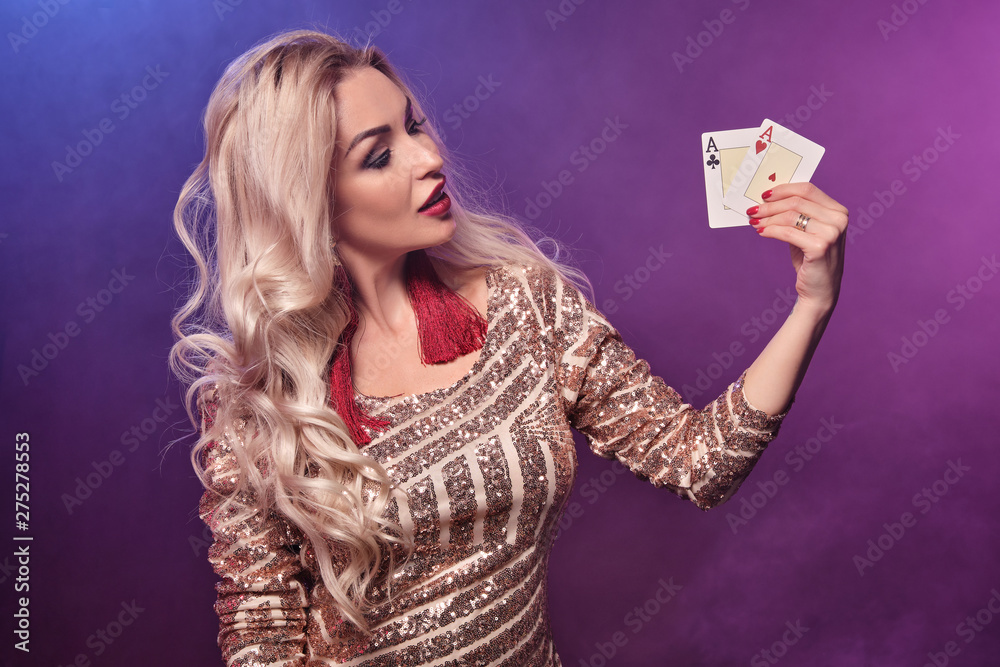 Blonde woman with a perfect hairstyle and bright make-up is posing with playing cards in her hands. Casino, poker. Blonde woman with a perfect hairstyle and bright make-up is posing with playing cards in her hands. Casino, poker.