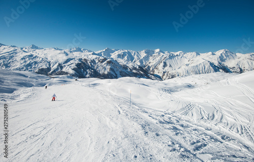 Skiers on a piste in alpine ski resort © Paul Vinten