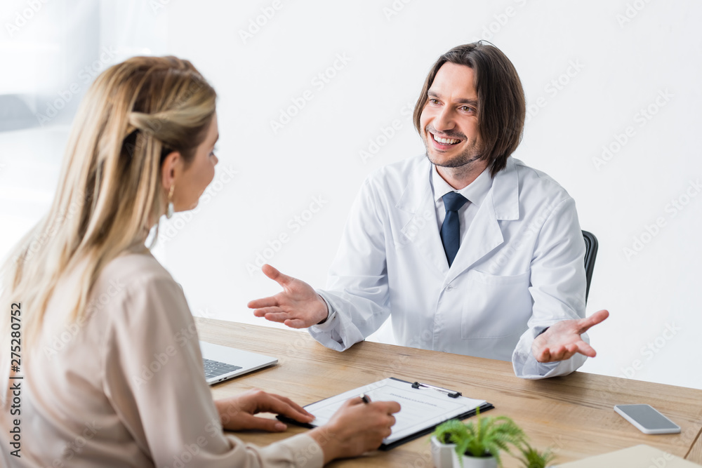 patient sitting with happy doctor behind wooden table and signing document patient sitting with happy doctor behind wooden table and signing document