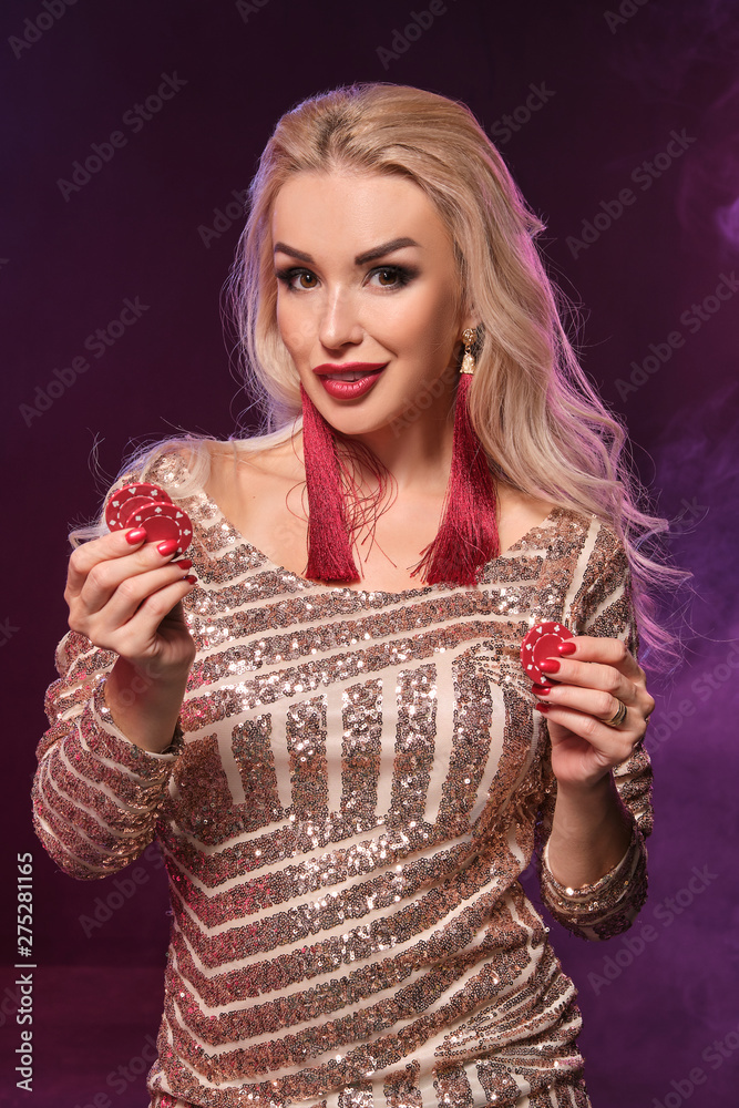Blonde woman with a perfect hairstyle and bright make-up is posing with gambling chips in her hands. Casino, poker. Blonde woman with a perfect hairstyle and bright make-up is posing with gambling chips in her hands. Casino, poker.
