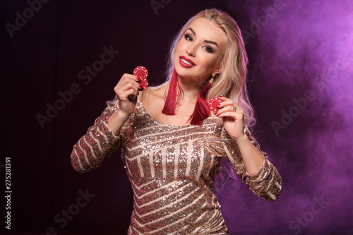 Blonde woman with a perfect hairstyle and bright make-up is posing with gambling chips in her hands. Casino  poker.