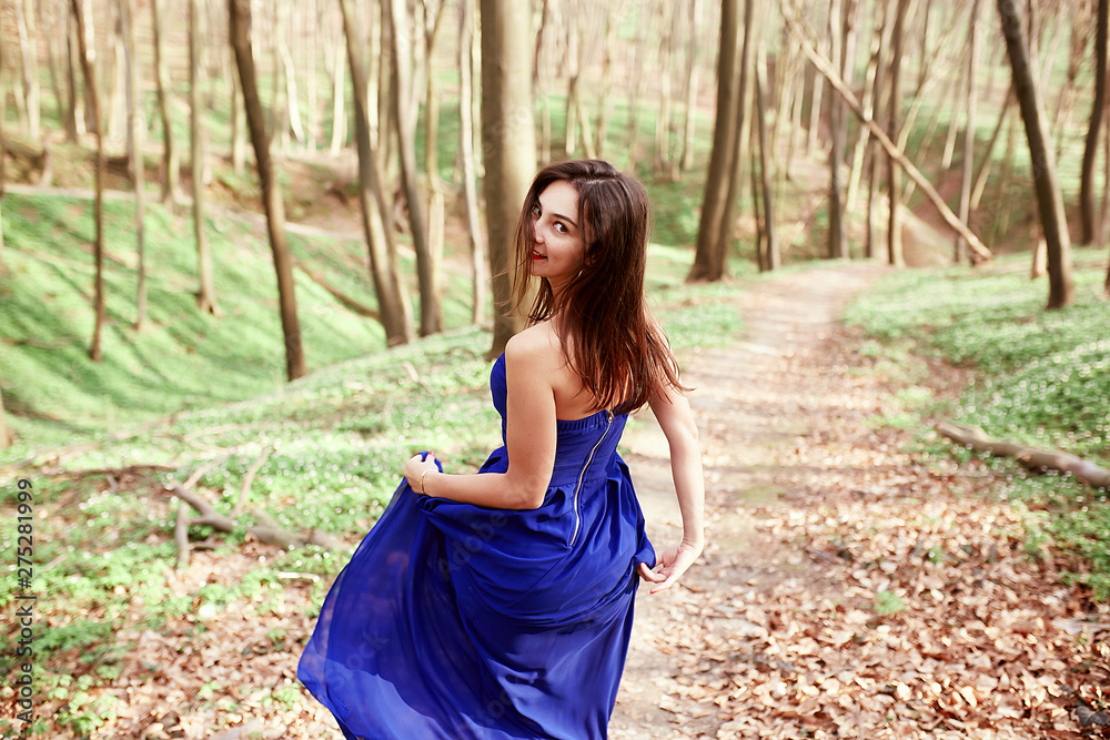 Happy girl in a blue dress running through the woods Happy girl in a blue dress running through the woods