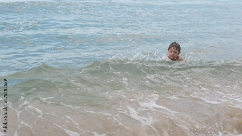 Happy child swims on the waves in the sea. A little girl swims in the sea. Happy child swims on the waves in the sea. A little girl swims in the sea.