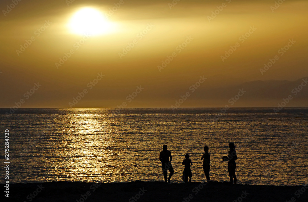 Silhouette of a family during sunset at the coast in Matala, Crete Silhouette of a family during sunset at the coast in Matala, Crete