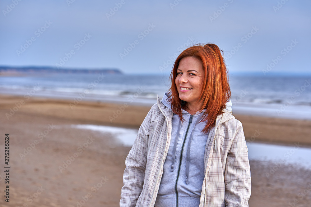 Portrait of a laughing middle-aged woman with red hair walking along the river bank. Sunny spring morning. Close-up. Portrait of a laughing middle-aged woman with red hair walking along the river bank. Sunny spring morning. Close-up.
