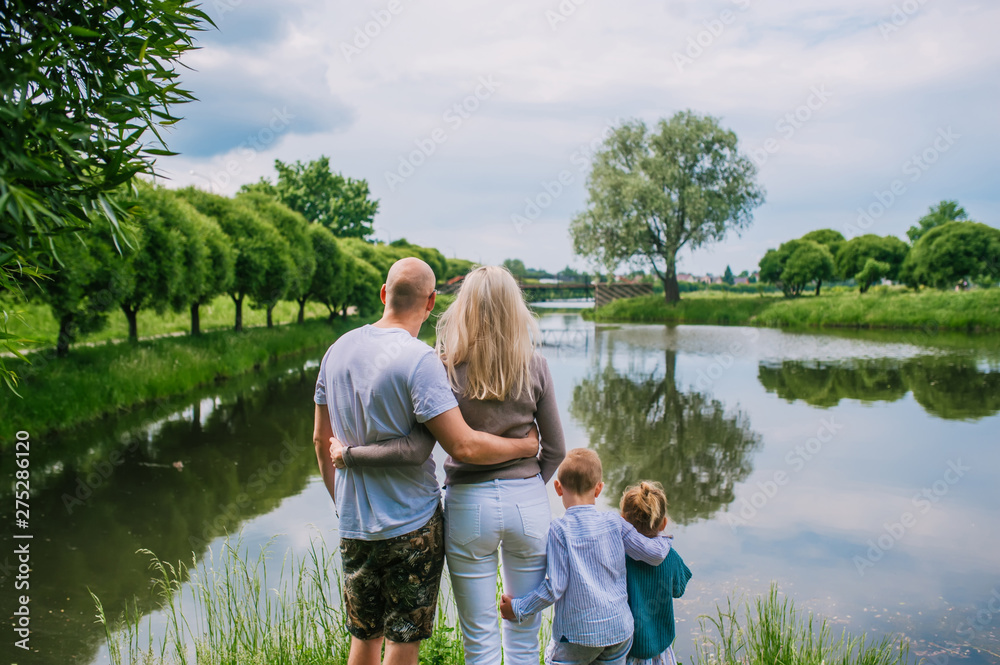 Two children, mother and father looking on lake in summer day back view. Two children, mother and father looking on lake in summer day back view.