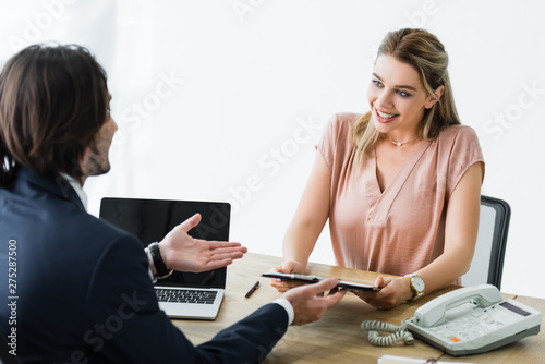 Schilderij op canvas happy woman looking at businessman and holding clipboard in hands