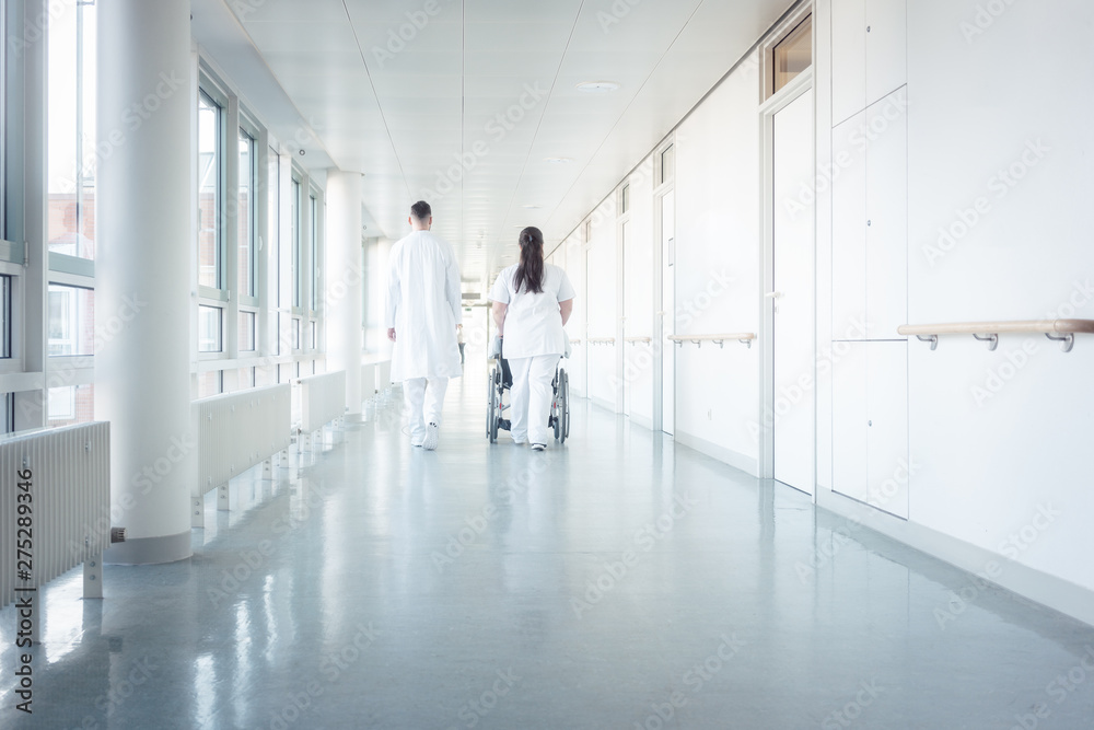 Doctor, nurse, and patient in wheelchair on hospital corridor