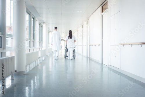 Doctor, nurse, and patient in wheelchair on hospital corridor © Kzenon