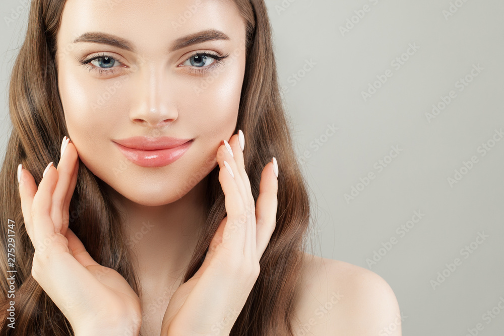 Young cute woman with clear skin and healthy brown hair on gray background Young cute woman with clear skin and healthy brown hair on gray background