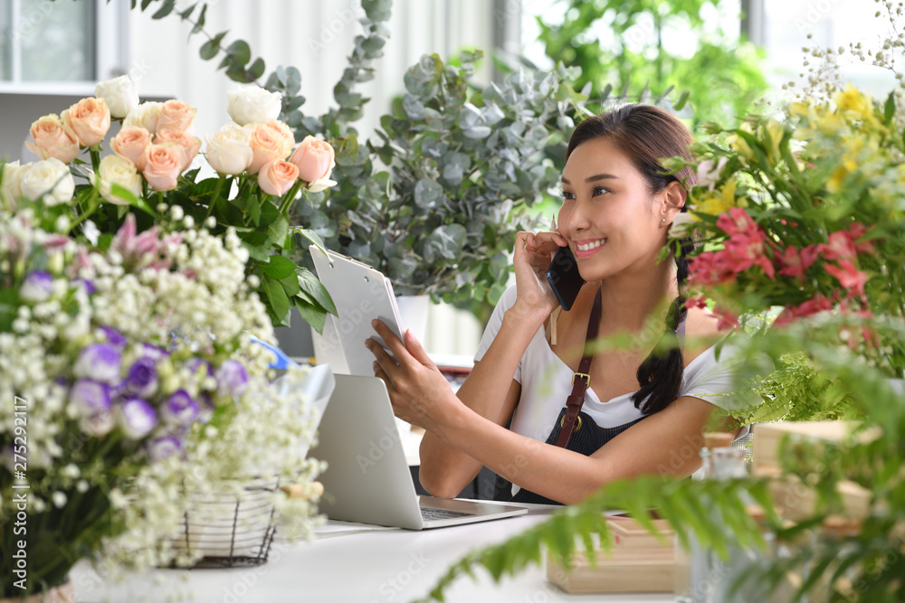 Young Asian woman entrepreneur/shop owner/ florist of a small flower shop business Young Asian woman entrepreneur/shop owner/ florist of a small flower shop business