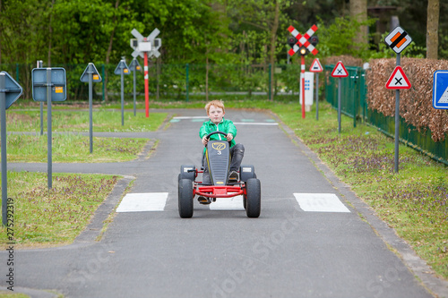 Φωτογραφία Adorable young boy on a go cart driving in a traffic learning parcours in an amu