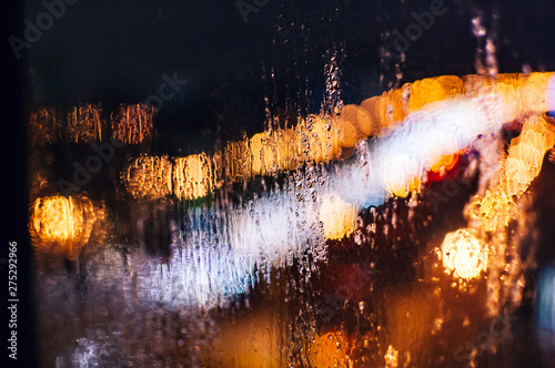Raindrops on the window, against the backdrop of the night city. Background, screen saver, wallpaper