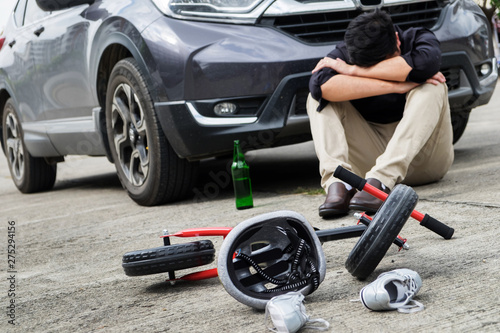 scared and stressed desperate drunken driver and bottle of beer in front of automobile crash car with child bike after traffic accident in city road