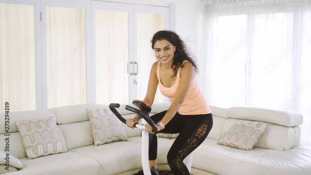 Attractive young woman sitting in living room while wearing sportswear and holding an apple fruit after exercising. Shot in 4k resolution Attractive young woman sitting in living room while wearing sportswear and holding an apple fruit after exercising. Shot in 4k resolution