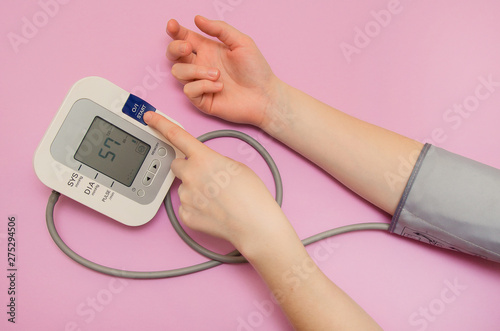 Wallpaper Mural Measurement of pressure. The woman takes care of her health by checking her blood pressure and pulse on her arm. lilac background Torontodigital.ca