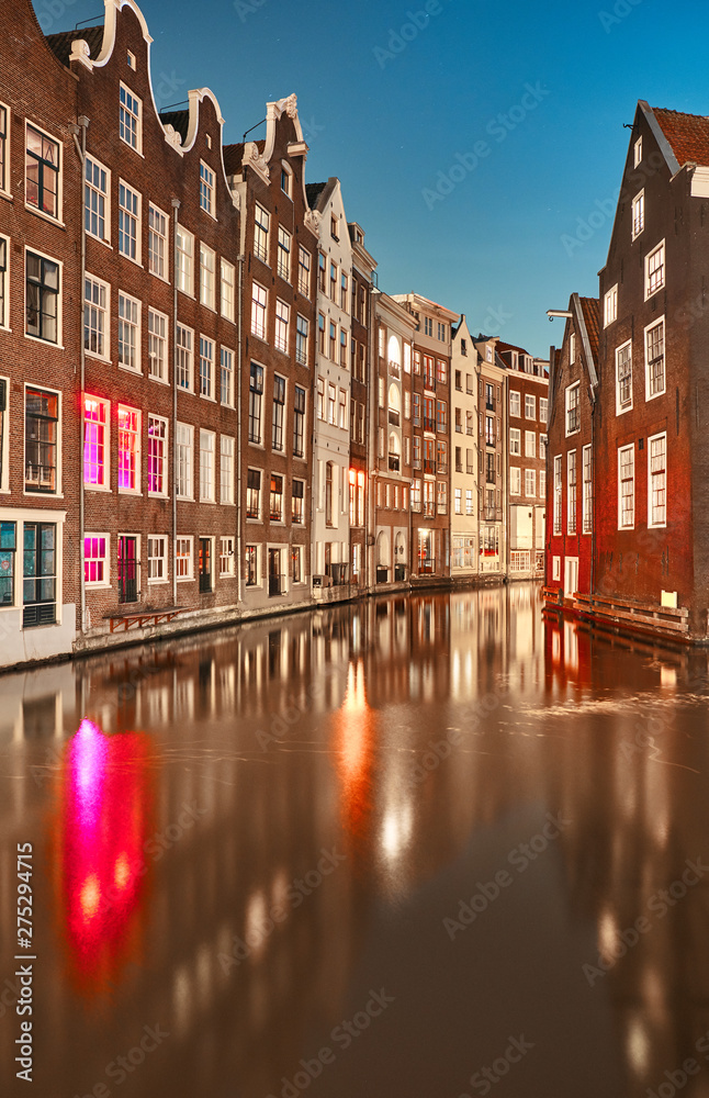 Fototapeta premium Canal between buildings at night in Amsterdam