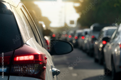 Luxury of cars stop by traffic jam in rush hour on the asphalt road. Traveling in the provinces during the bright period. Open light brake. with shadow of tree.